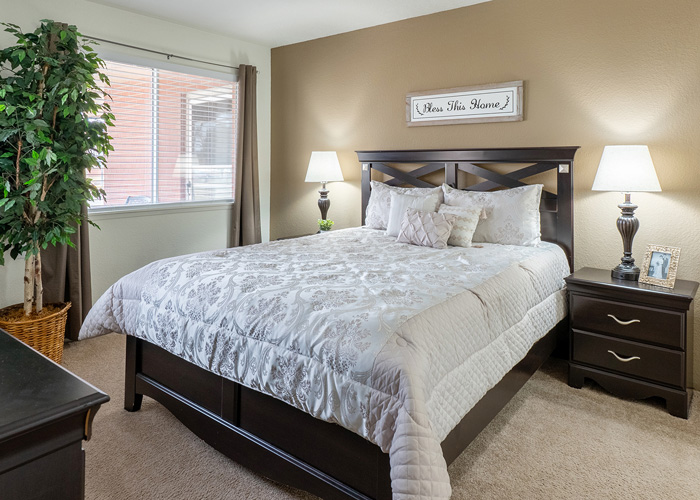 A cozy bedroom with a queen-sized bed, elegant bedding, bedside lamps, a large window, and warm decor for a serene and welcoming feel.