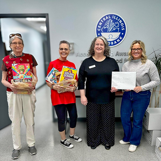Residents and team members smile with a representative of a local food bank during a community outing to donate.