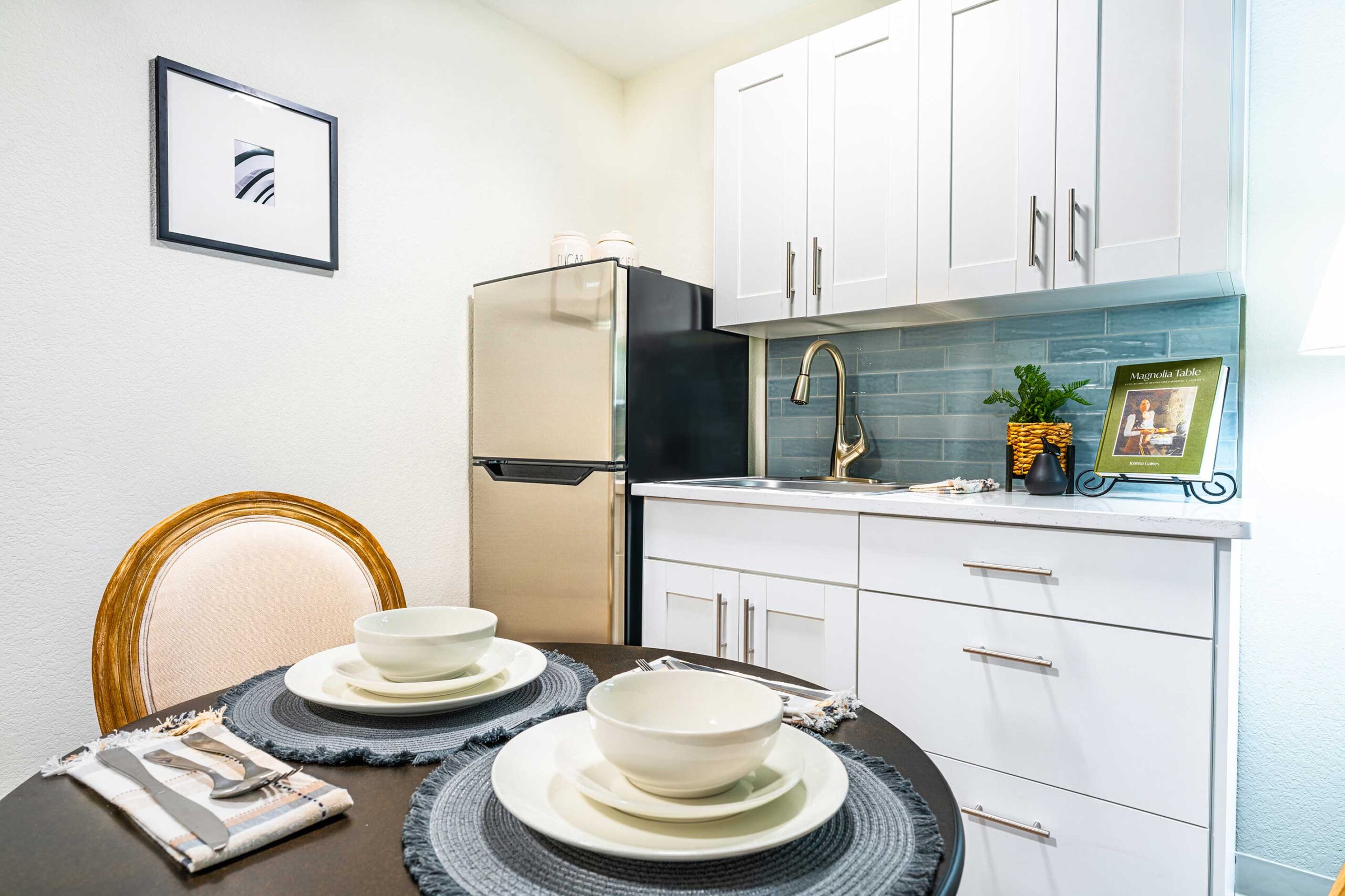Newly renovated apartment kitchen at The Montvale Senior Living in Springfield, Illinois, completed in 2025 and featuring blue subway tile backsplash, stainless steel refrigerator and white cabinetry.