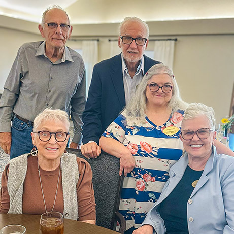 Five senior residents smile brightly during a relaxed moment at Montvale Senior Living.